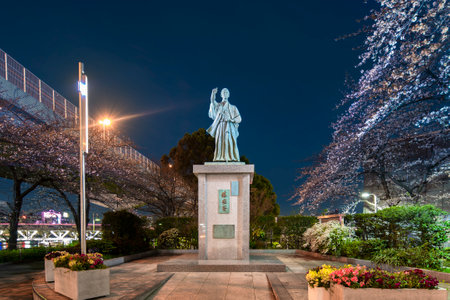 tokyo, japan - march 25 2020: Cherry blossoms and bronze statue of the samurai and founder of the modern navy Kaishu Katsu made in 2003 by the sculptor Kiuchi Reichi on the Uruoi square of the town hall of Kuroda at night.のeditorial素材