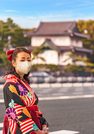 Tokyo, Japan - March 01 2020: Japanese woman in hakama kimono in front of the dungeon Edoj? sakurada tatsumiyagura with moats lined with pine trees outside of the Tokyo Imperial Palace.のeditorial素材
