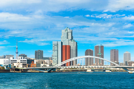Arch bridge of Tsukiji Ohashi on the Sumida river crossed by Kanni Street with the skyscrapers of the Tsukiji district and the Tokyo Skytree tower in the background.のeditorial素材