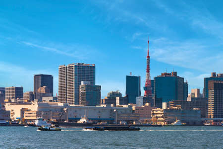 Barges towed by Tugboats sailing in front of the Shibaura Terminal on Tokyo port with the skyscrapers of Shiba district and the Tokyo Tower in the back.の写真素材
