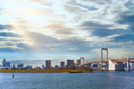 Seascape of the Bird Island of Odaiba Bay in front of the double-layered suspension Rainbow Bridge in the port of Tokyo with altostratus clouds in the sky.の写真素材