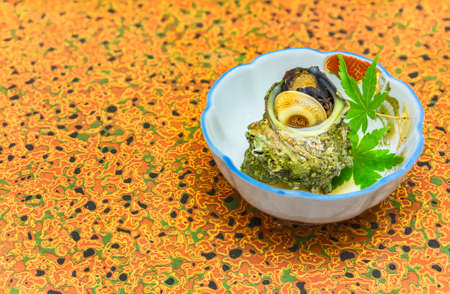 High-class japanese cuisine of traditional Tsubo-yaki steamed Sazae horned turban sea snail in a...