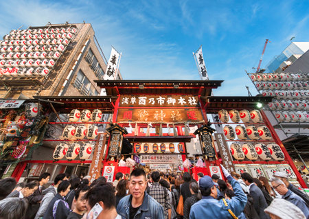 akihabara, japan - november 08 2019: Crowds agglutinated at the gate of the Ootori shrine decorated with paper lanterns to buy auspicious bamboo rakes at Tori-no-Ichi Fair to have success in businessのeditorial素材