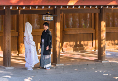 tokyo, japan - october 10 2020: Traditional Japanese shinto wedding of a couple in black haori kimono and white shiromuku under a lantern ornated of the imperial coat of arm in the Meiji Shrine.のeditorial素材