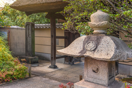 tokyo, japan - november 05 2020: Japanese stone lantern at side of the Tamonji-Sanmon main gate with a thatched roof in the Buddhist Tamonji temple designated tangible cultural property of Sumida wardのeditorial素材