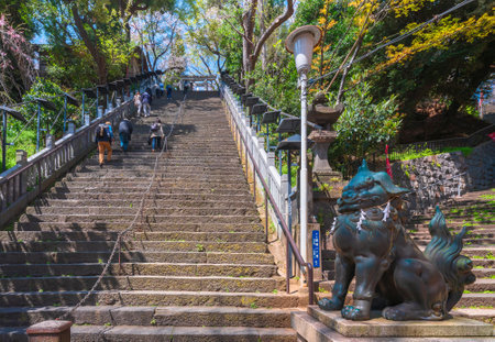 tokyo, japan - april 13 2020: Bronze statue of a Japanese Komainu lion protecting the worshipers carefully climbing the steep stairs of success of the Shintoist Atago shrine on the Mt. Atago.のeditorial素材