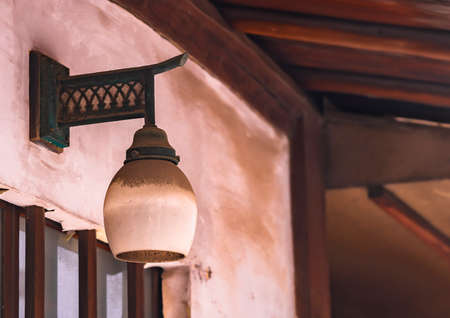 Close up on a dusty sconce light fixture also called wall light covered by a white lacquered glass under the eave of a traditional geisha house in the Kakurenbo yokocho alley of Kagurazaka.の写真素材