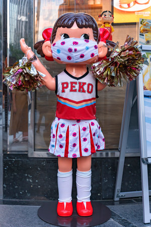 tokyo, japan - august 30 2021: Life sized mascot figurine of the Fujiya confectionery stores called Peko-chan wearing a mask and cheerleader outfit for support during  pandemic in Ginza.のeditorial素材