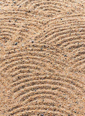 Closeup on a texture background of gravels in a Japanese zen dry garden made by priest with a rake depicting patterns recalling waves or rippling water known as samon or hÅkime in Hama-rikyu Gardens.の写真素材