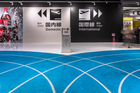 tokyo, japan - december 06 2020: Arrows and icons leading to the international and domestic flights departure gates on the wall of the Narita International Airport which floor is a blue pathway.のeditorial素材