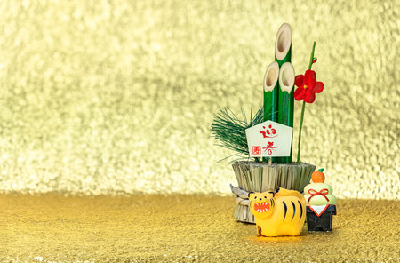 Japanese New Year's Greeting Card of a bamboo kadomatsu with the words congratulations for the welcoming spring, a kagami mochi rice cake and a cute figurine of a roaring tiger on a golden background.の写真素材