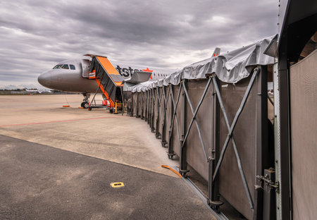 tokyo, japan - december 06 2021: Jet boarding bridge leading passengers to an airbus plane from Japanese low-cost carrier airline jetstar airways on the apron of the Narita international airport.のeditorial素材
