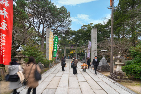 kyushu, japan - december 08 2021: Japanese families with kids in kimono on the sandÅ path of Miyajidake Shrine surrounded by stone lanterns and votive pillars leading to a Torii portal.のeditorial素材