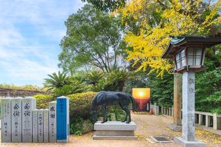 kyushu, japan - december 08 2021: Stone lantern in front of a divine Shinme horse bronze statue offered to Japanese Miyajidake Shrine with a poster of the Path of lights in background in fukutsu cityのeditorial素材