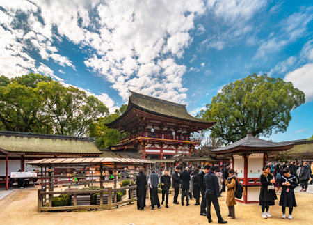 kyushu, fukuoka - december 07 2019: Japanese tourists and students in school uniforms reading omikuji votive strips papers in front of the two-storied RÅmon gate of the Japanese Dazaifu shrine.のeditorial素材
