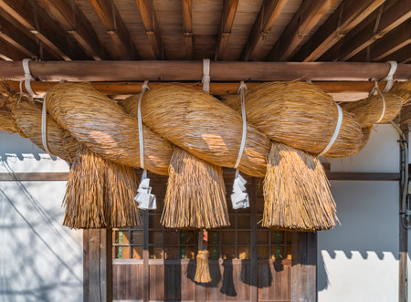 nagasaki, kyushu - december 14 2021: Japanese giant Oo-Shimenawa rice straw or hemp rope festooned with white shide paper streamers below the awning of the shintoist Kazagashira-Daigongen shrine.のeditorial素材