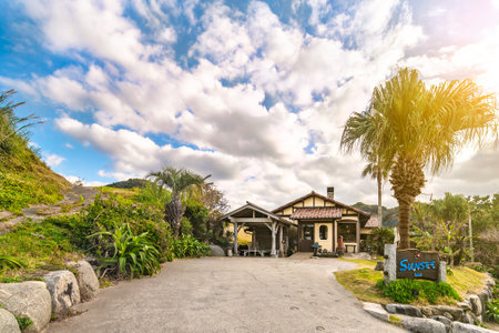 kyushu, fukuoka - december 07 2021: Japanese restaurant Beach Cafe Sunset along the Futamigaura beach surrounded by tropical plants and palm trees with horseshoes leading to the entrance.のeditorial素材