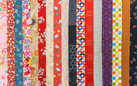 All kinds of colorful and vivid Japanese furoshiki cloths designs including florals, fauna and geometric patterns like waves, circles, leaves, rabbits, owls or cranes stacked in a stripes presentationの写真素材