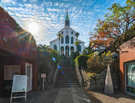 nagasaki, kyushu - dec 13 2022: Glistening in the sunlight, behold the majestic Basilica of the Twenty-Six Holy Martyrs of Japan, known as Åura Church, standing tall above its stairs and palm trees.のeditorial素材
