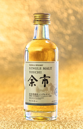 Hokkaido, japan - April 05 2023: Closeup on a small bottle miniature of single malt Yoichi from the Japanese distiller Nikka Whiskey displayed on a luxurious golden surface in a shallow depth of field.のeditorial素材