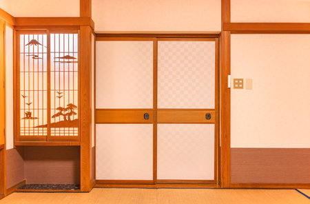 Wall of a typical traditional Japanese room featuring tatami mats covering the floor, fusuma doors and shoji window made of rice paper with wooden decorationsの写真素材