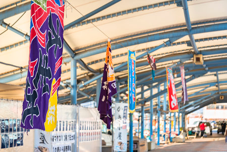 kyushu, fukuoka - december 23 2022: Japanese tairyÅ-bata flags used on fishermen boats adorned with a tabanenoshi fortune motif hung below the hangar of the Tsuyazaki fishing port in Kyushu.のeditorial素材