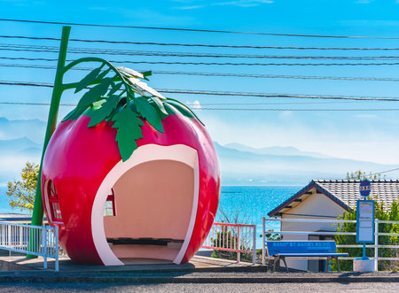 kyushu, japan - december 10 2022: Kofukai bus stop designed as a giant tomato fruit in front of the Ariake sea of Isahaya along the tokimeki fruit-shaped bus stop avenue against a blue sky.のeditorial素材