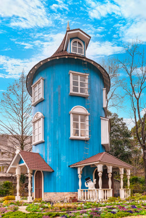 japan, saitama - march 26 2023: The blue wooden Moomin house called Muumitalo with the cute Moominpappa wearing his black top hat and cheerfully waving with his hand in the Japanese Moominvalley park.のeditorial素材
