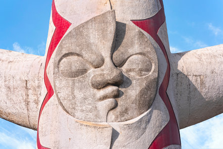 japan, osaka - Dec 4 2022: Close-up on the plaster face of the Japanese Tower of the Sun or taiyou no tou created by Taro Okamoto for Expo '70 which contains a Tree of Life against a bright blue sky.のeditorial素材
