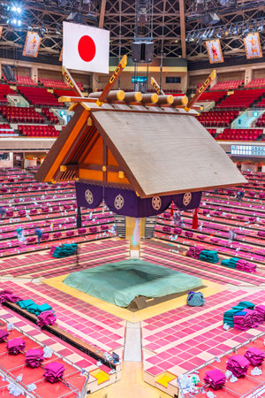 tokyo, ryogoku - jan 14, 2023: The sumo wrestling dohyÅ of the Kokugikan Arena, with a Japanese Shinto Tsuriyane roof adorned with a hinomaru national flag hanging above the empty arena after a match.のeditorial素材