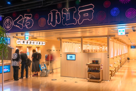 tokyo, ginza - may 14 2024: Japanese Kura Revolving Sushi Bar interior with self-checkout kiosks and wooden booths where customers ordering sushi in a modern setting inspired by koedo cultural style.のeditorial素材