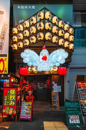 Osaka, Namba Sennichimae - Dec 7 2024: Vibrant night facade of Japanese restaurant Yakitori Jiro, attracting tourists with its giant illuminated chicken lantern and traditional chochin paper lanterns.のeditorial素材