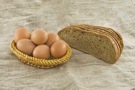 Still-life. Vegetarian products: rye bread from a flour of a rough grinding and the eggs lying in a...