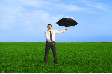 Happy businessman standing with umbrella in the meadowの写真素材