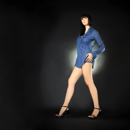 Fashion brunette with long legs posing in the darkの写真素材