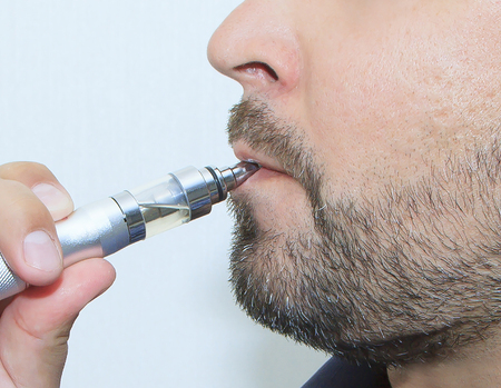 Profile view of young man smoking electronic sigarette