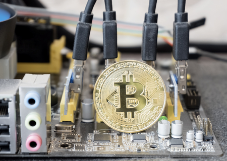 Gold bitcoin coin over mother board with risers