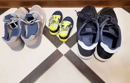 Dad, mom, son - a happy family. Three pairs of sneakers on the floorの写真素材