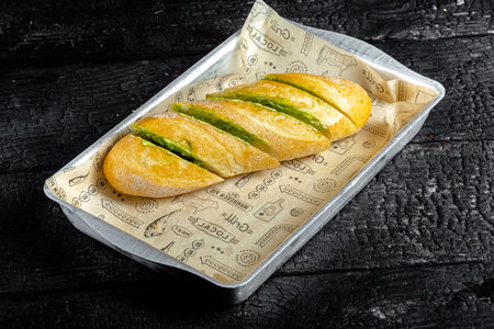 Baguette with asparagus and cheese on black wooden background