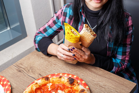 Young woman eating pizza in the cafe, close-up view.の写真素材