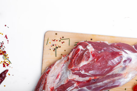 Raw pork meat on a cutting board with spices and herbs on a white backgroundの写真素材