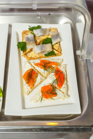 canape with salmon and cream cheese on a white plate in a restaurantの写真素材