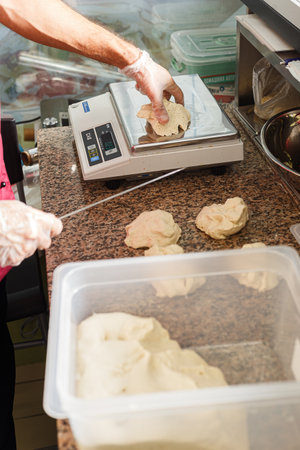 Close-up of a female baker weighing dough for bread in a commercial kitchen