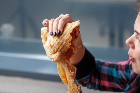 Woman eating tasty doner kebab in cafe, closeupの写真素材