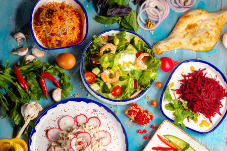 Vegetable salad with shrimps, prawns, cabbage, cucumbers, tomatoes, radishes, onions, herbs and spices on blue wooden backgroundの写真素材