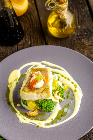 Fried fish fillet with broccoli and egg on a white plate