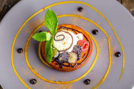 Delicious tartlets with berries and ice cream on a plate.の写真素材