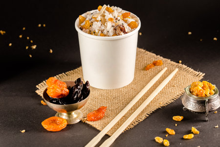 White paper cup with dried fruits and chopsticks on a black background