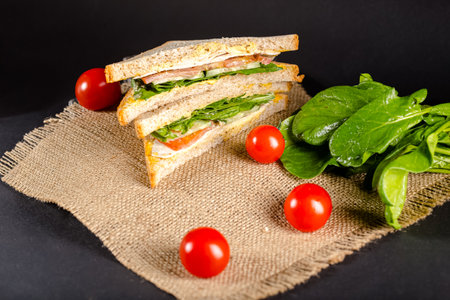 Sandwich with ham, cheese, tomatoes and spinach on black backgroundの写真素材