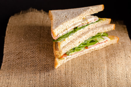 Sandwich with ham, cheese and arugula on a black backgroundの写真素材